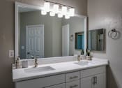 Thumbnail 11 of 38 - Double vanity bathroom with white countertop and mirror at Wyndchase Aspen Grove Apartments, Franklin, TN 37067
