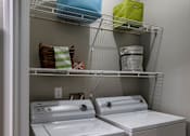 Thumbnail 12 of 38 - In unit washer and dryer with overhead shelving at Wyndchase Aspen Grove Apartments, Franklin, TN 37067