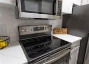 Thumbnail 4 of 38 - Modern kitchen with stainless steel appliances and cooktop at Wyndchase Aspen Grove Apartments, Franklin, TN 37067