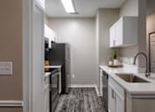 Thumbnail 3 of 38 - Galley kitchen with stainless steel appliances and white countertops at Wyndchase Aspen Grove Apartments, Franklin