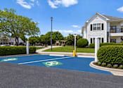 Thumbnail 11 of 33 - A parking lot with a blue painted area and a white building in the background.