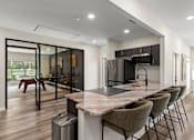 Thumbnail 16 of 33 - A modern kitchen with a marble countertop and a dining table with chairs.