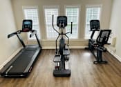 Thumbnail 20 of 20 - Three exercise machines are lined up in a room.