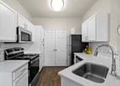 Thumbnail 30 of 33 - A kitchen with white cabinets and a black refrigerator.