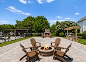 Thumbnail 7 of 33 - A fire pit in the middle of a patio surrounded by chairs.