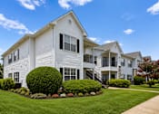 Thumbnail 9 of 33 - A white two-story house with a well-manicured lawn and a clear blue sky.
