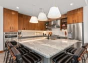 Thumbnail 20 of 40 - a large kitchen with a marble counter top and chairs at The Colony, North Carolina
