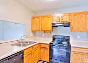 Thumbnail 5 of 17 - A kitchen with wooden cabinets and a black stove top oven.