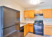 Thumbnail 11 of 17 - A kitchen with a black refrigerator and wooden cabinets.