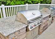 Thumbnail 6 of 17 - A silver BBQ grill on a stone and concrete patio.