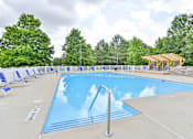 Thumbnail 14 of 17 - A large outdoor swimming pool surrounded by trees and lounge chairs.