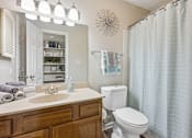 Thumbnail 9 of 19 - A bathroom with a toilet, sink, and shower curtain.