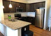Thumbnail 12 of 14 - A kitchen with a granite counter top and stainless steel appliances.