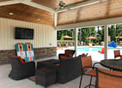 Thumbnail 5 of 14 - A patio with a television, chairs, and a pool.