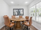 Thumbnail 16 of 17 - A conference room with a round table and chairs.