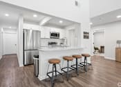 Thumbnail 11 of 17 - A kitchen with a bar and stools in the middle of the room.