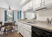 Thumbnail 6 of 17 - A kitchen with a black dishwasher and a fan.