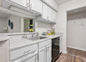 Thumbnail 3 of 17 - A kitchen with white cabinets and a marble countertop.