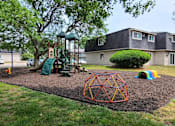 Thumbnail 30 of 31 - A playground with a swing set, a slide, and a climbing structure.