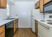 Thumbnail 15 of 19 - a kitchen with white appliances and wooden cabinets at Tides on Southern, Mesa, AZ