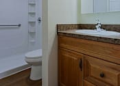 Thumbnail 7 of 16 - A bathroom with a toilet, sink, and wooden cabinet.
