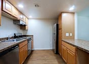 Thumbnail 2 of 16 - A kitchen with wooden cabinets and a black fridge.