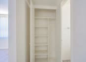 Thumbnail 18 of 21 - a walk in closet in a bedroom with white walls and white shelves