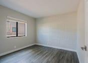 Thumbnail 11 of 15 - A room with a window and a wooden floor.