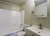 Thumbnail 8 of 15 - A white toilet sits next to a white bathtub in a bathroom.