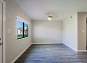 Thumbnail 4 of 15 - A spacious room with a ceiling fan and a window overlooking a building.