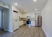 Thumbnail 5 of 15 - A kitchen with white appliances and wooden floors.