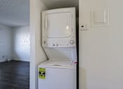 Thumbnail 10 of 25 - A white dishwasher with a yellow caution label on the door is in a room with white walls.
