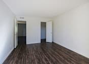 Thumbnail 11 of 25 - A room with white walls and wood flooring with two doors.