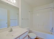 Thumbnail 10 of 17 - A white bathroom with a sink, toilet, and bathtub.