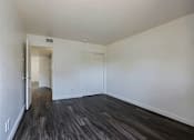Thumbnail 19 of 30 - A room with a wooden floor and white walls.