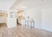 Thumbnail 2 of 27 - an open living room and kitchen with white walls and wood flooring