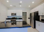 Thumbnail 3 of 23 - a modern kitchen with stainless steel appliances and black counter tops