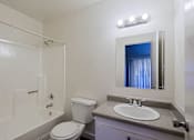 Thumbnail 21 of 30 - A bathroom with a toilet, sink, and mirror.