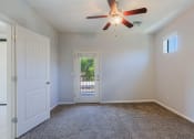 Thumbnail 9 of 23 - an empty room with a ceiling fan and a door to a balcony