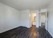 Thumbnail 15 of 30 - A room with white walls and wood flooring with a doorway leading to another room.