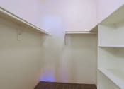 Thumbnail 16 of 21 - a walk in closet with white walls and shelves and two white shelves on the wall