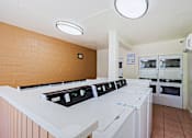 Thumbnail 24 of 25 - A row of white ovens are lined up in a room.