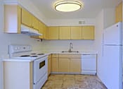 Thumbnail 2 of 25 - A kitchen with white appliances and wooden cabinets.