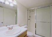 Thumbnail 6 of 25 - A white bathroom with a sink, toilet, and shower.