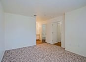 Thumbnail 7 of 17 - A large empty room with a carpeted floor and white walls.