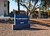 Thumbnail 1 of 21 - A sign for River North Apartments stands in front of a building.