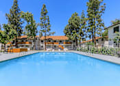 Thumbnail 19 of 28 - the swimming pool surrounded by trees in front of apartments with an orange roof at Tides on McDowell, Phoenix, 85035