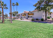 Thumbnail 17 of 28 - a white building with wooden balconies with palm trees and grass in front of it at Tides on McDowell, Arizona, 85035