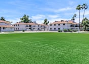 Thumbnail 9 of 28 - A large grassy field in front of a row of apartments at Tides on McDowell, AZ 85035
