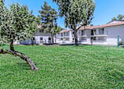Thumbnail 12 of 28 - a yard with trees and apartments in the background at Tides on McDowell, Phoenix, 85035